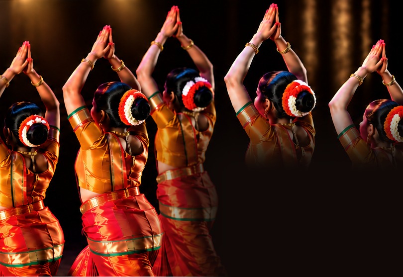Bharatanatyam-danseressen in oranje kostuums, met de rug naar de camera en de handen boven het hoofd